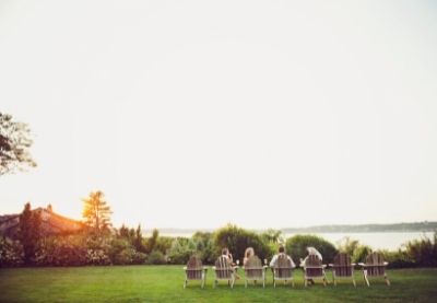 Line of people in lawn chairs facing the ocean at sunset at Castle Hill Inn in Newport, RI