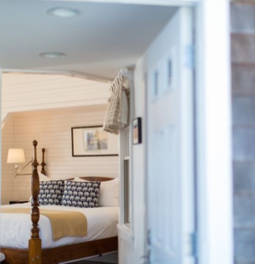 White door in front of large bed with blue pillows at Castle Hill Inn in Newport, RI