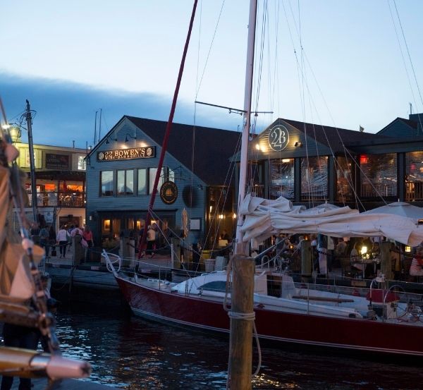 Exterior of building near sailboat docked at sea at nighttime near Castle Hill Inn in Newport, RI