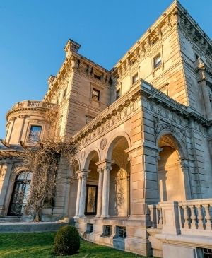 Exterior of large stone mansion in front of trees and shrubbery at Castle Hill Inn in Newport, RI