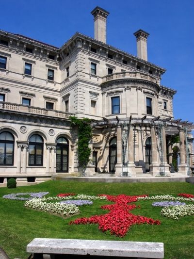 Exterior of large stone mansion in front of flowers and stone bench at Castle Hill Inn in Newport, RI