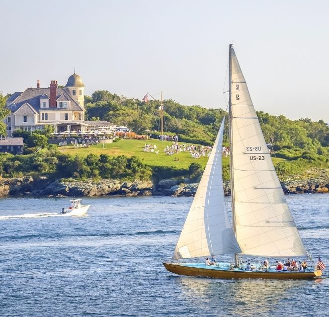 Sailboat on ocean with people on it overlooking Castle Hill Inn in Newport, RI