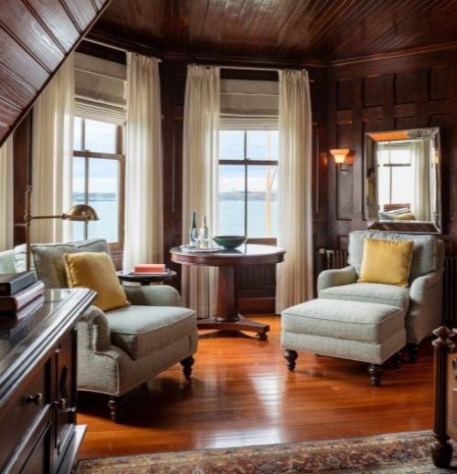 Two chairs inside wooden room near wooden table overlooking ocean at Castle Hill Inn in Newport, RI