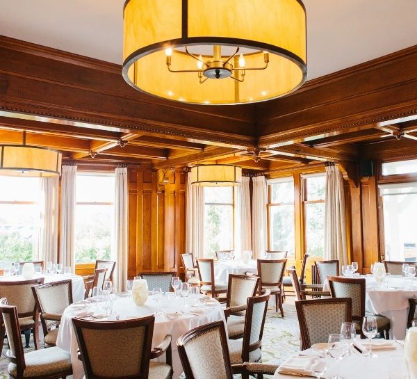 Dining room with tables and chairs with white linens and glassware at Castle Hill Inn in Newport, RI