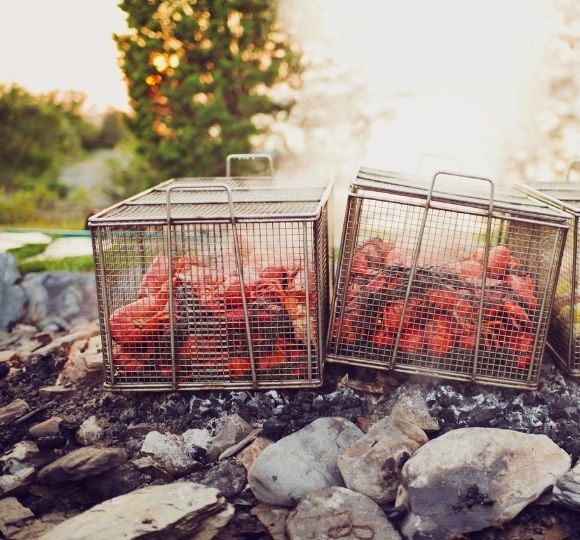 Cages of lobsters on top of rocky beach in front of trees at Castle Hill Inn in Newport, RI