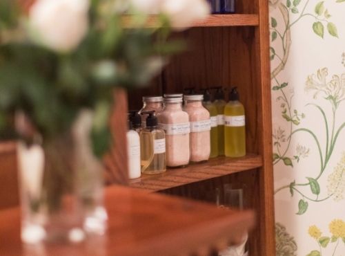 Various bottles on top of wooden shelf behind vase of flowers at Castle Hill Inn in Newport, RI