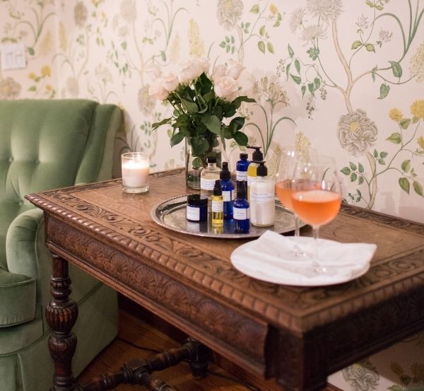 Various bottles on top of tray near candles, glasses of wine and green chair at Castle Hill Inn in Newport, RI