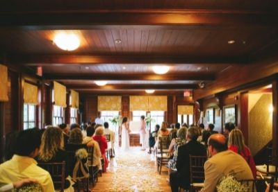 Indoor wedding setup with people sitting in chairs looking forward toward altar at Castle Hill Inn in Newport, RI