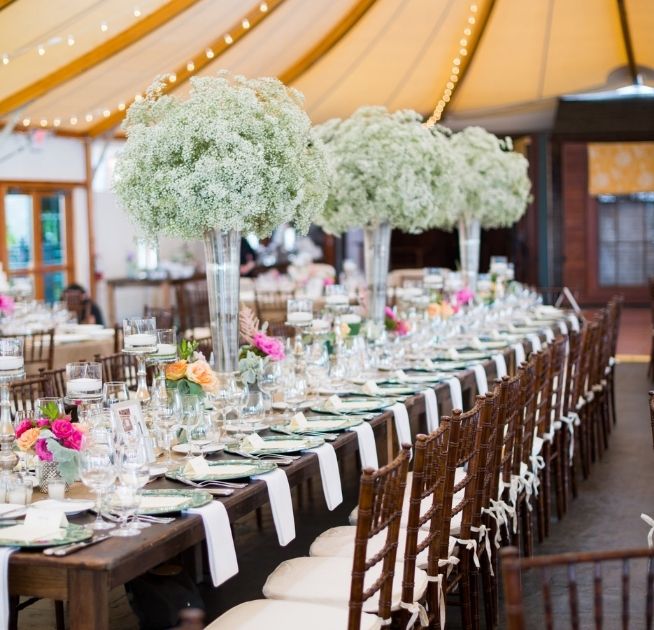 Long wooden table with white napkins, and black and white chairs with floral arrangements and glassware at Castle Hill Inn in Newport, RI